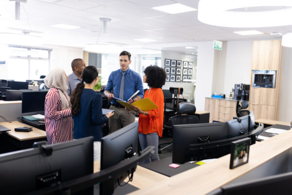 Happy diverse female and male business people talking and working in office